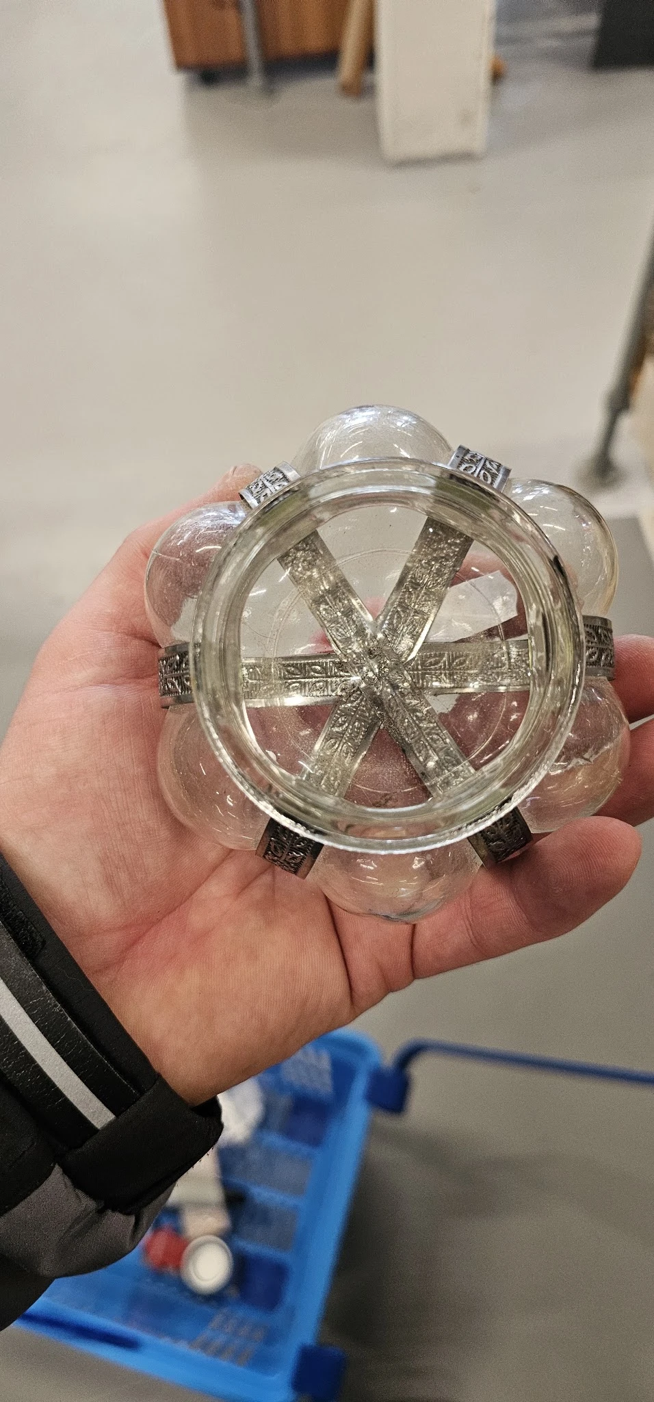 Close-up van een rond glazen decoratief item met metalen details en paars/roze vloeistof erin