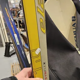 Close-up van gele ski's met zwarte bindingen, gestapeld naast blauwe ski's