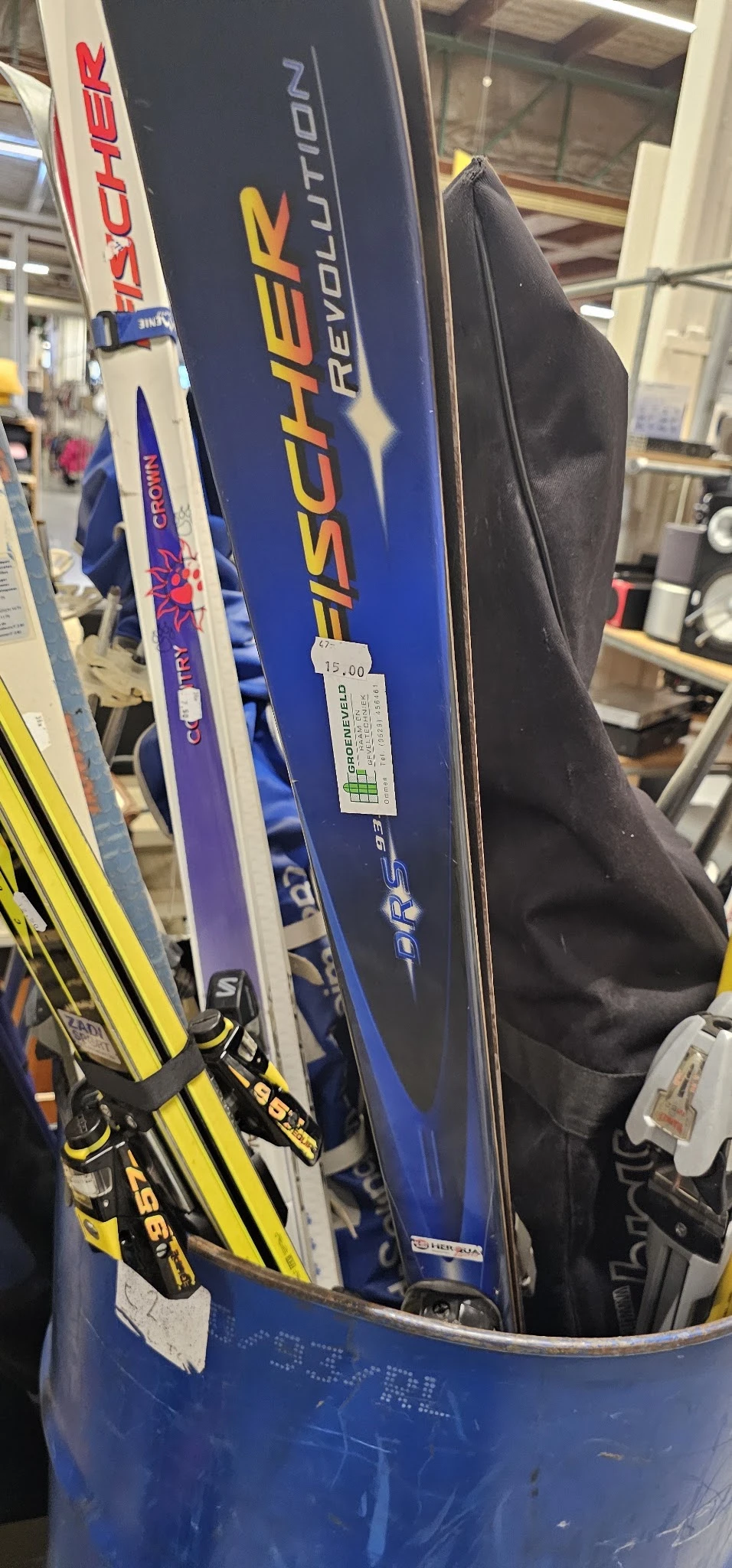 Ski's en skistokken in verschillende kleuren tegen elkaar geleund in de winkel