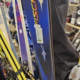 Ski's en skistokken in verschillende kleuren tegen elkaar geleund in de winkel