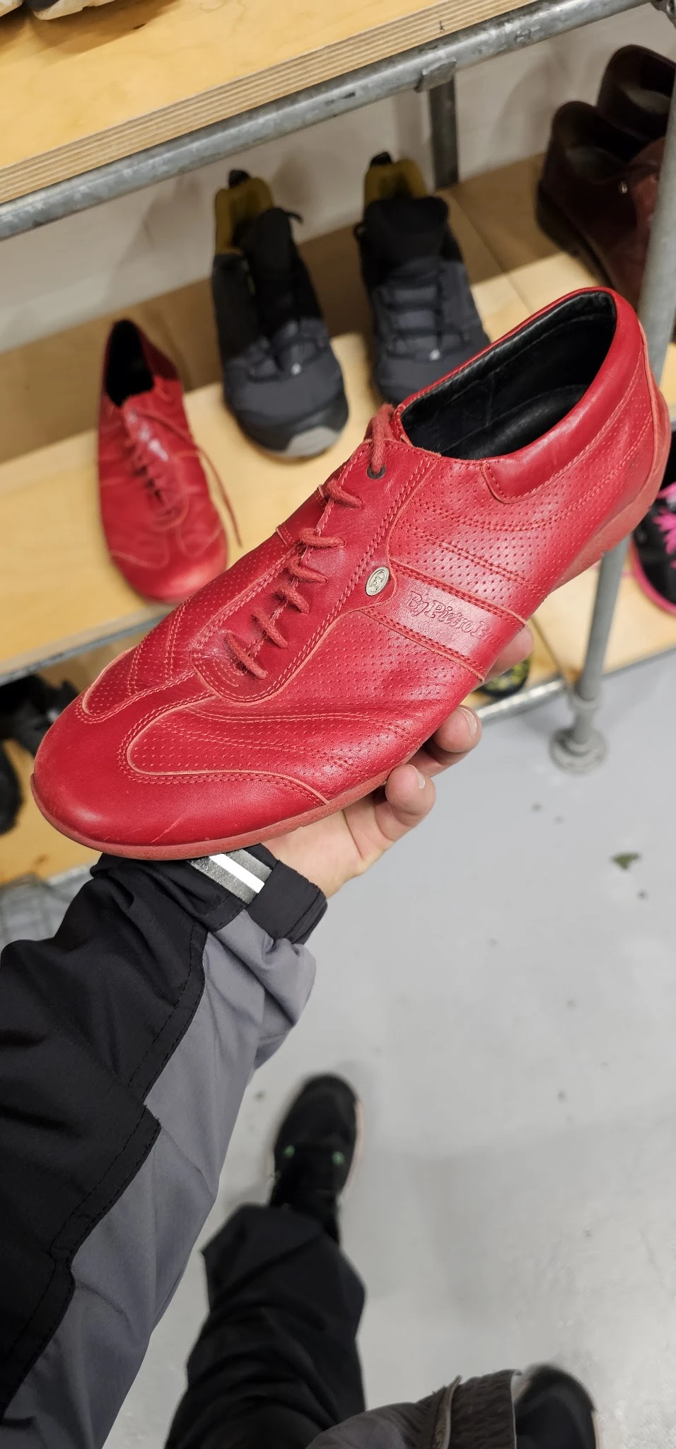 Rode leren sportschoen in hand, close-up met zichtbaar merk en details