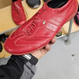 Rode leren sportschoen in hand, close-up met zichtbaar merk en details