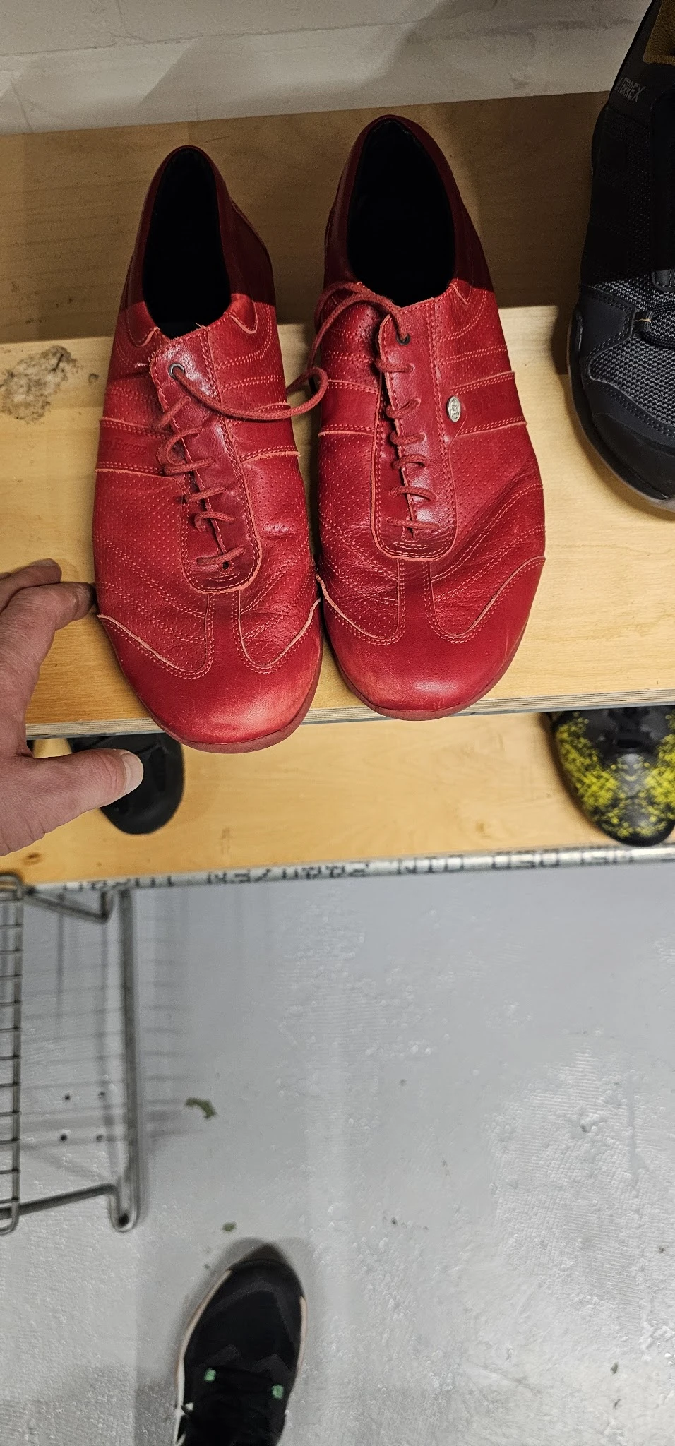 Close-up van twee rode leren schoenen met decoratieve stiksels, gemeten met een liniaal