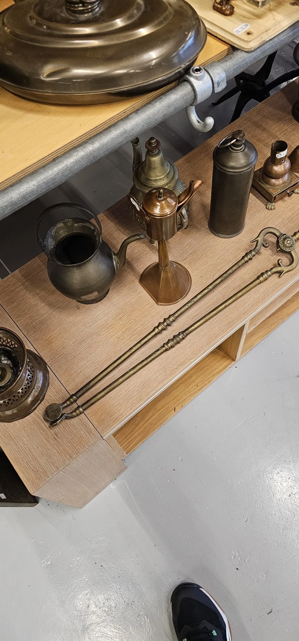 Verzameling antieke koperen en metalen huishoudartikelen op houten tafel, waaronder kandelaars en gereedschap