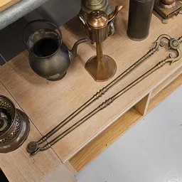 Verzameling antieke koperen en metalen huishoudartikelen op houten tafel, waaronder kandelaars en gereedschap