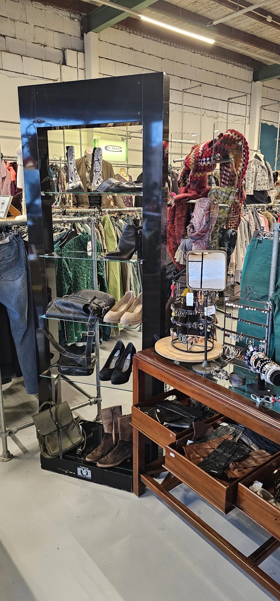 Rekken met tweedehands kleding, schoenen en accessoires in kringloopwinkel