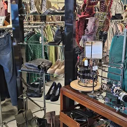 Rekken met tweedehands kleding, schoenen en accessoires in kringloopwinkel