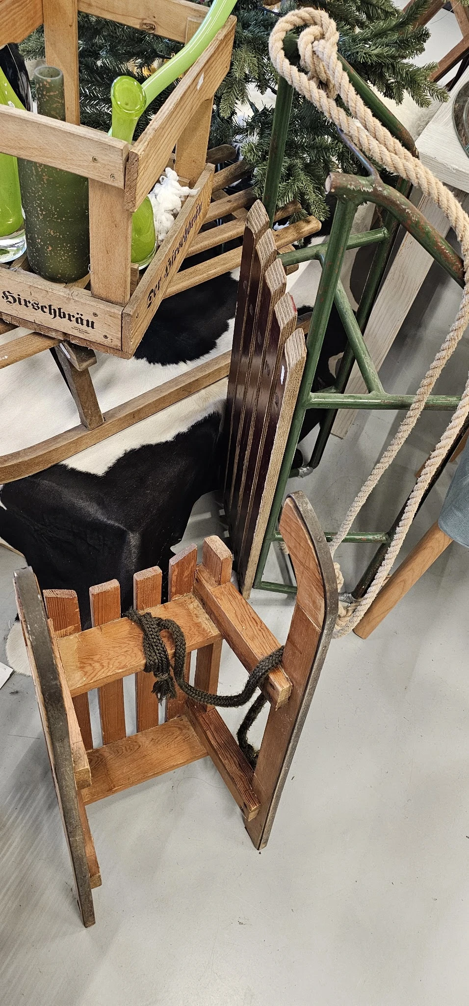 Verschillende tweedehands meubelen: houten stoelen, zwarte pouf en groen metalen frame