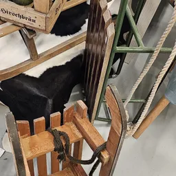 Verschillende tweedehands meubelen: houten stoelen, zwarte pouf en groen metalen frame