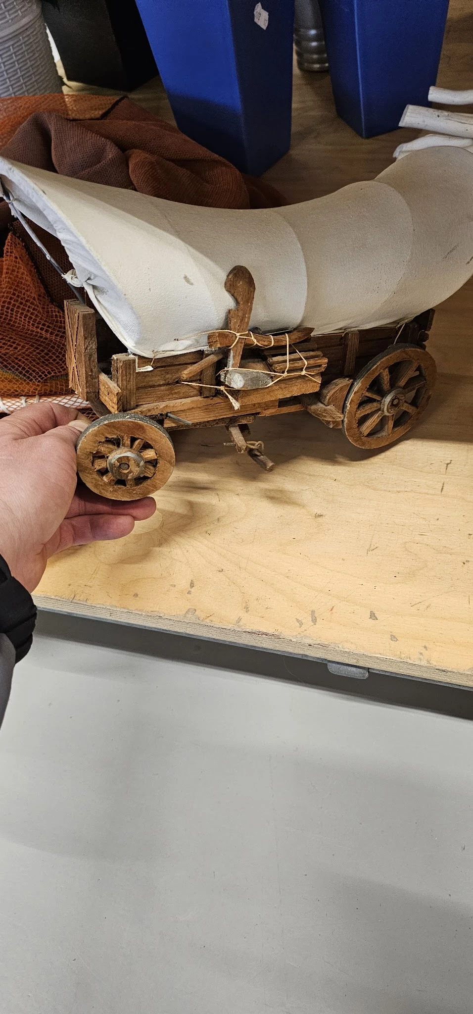 Close-up van een houten wiel van een miniatuurtrekwagen in iemands hand