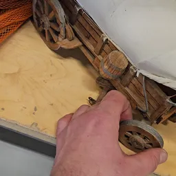 Close-up van een hand die een houten voorwerp of interieur vasthoudt