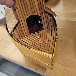 Gele houten vogelhuisje met open zijkant en zwart gaas, zonder voorkant