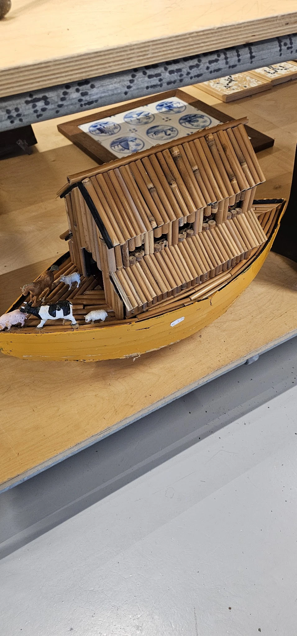 Miniatuurnschip met gele romp en houten details op display