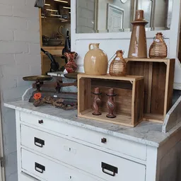 Uitgestalde decoratieve items: houten opbergkisten, keramische kruiken, koperen kandelaars en andere antieke voorwerpen op ee