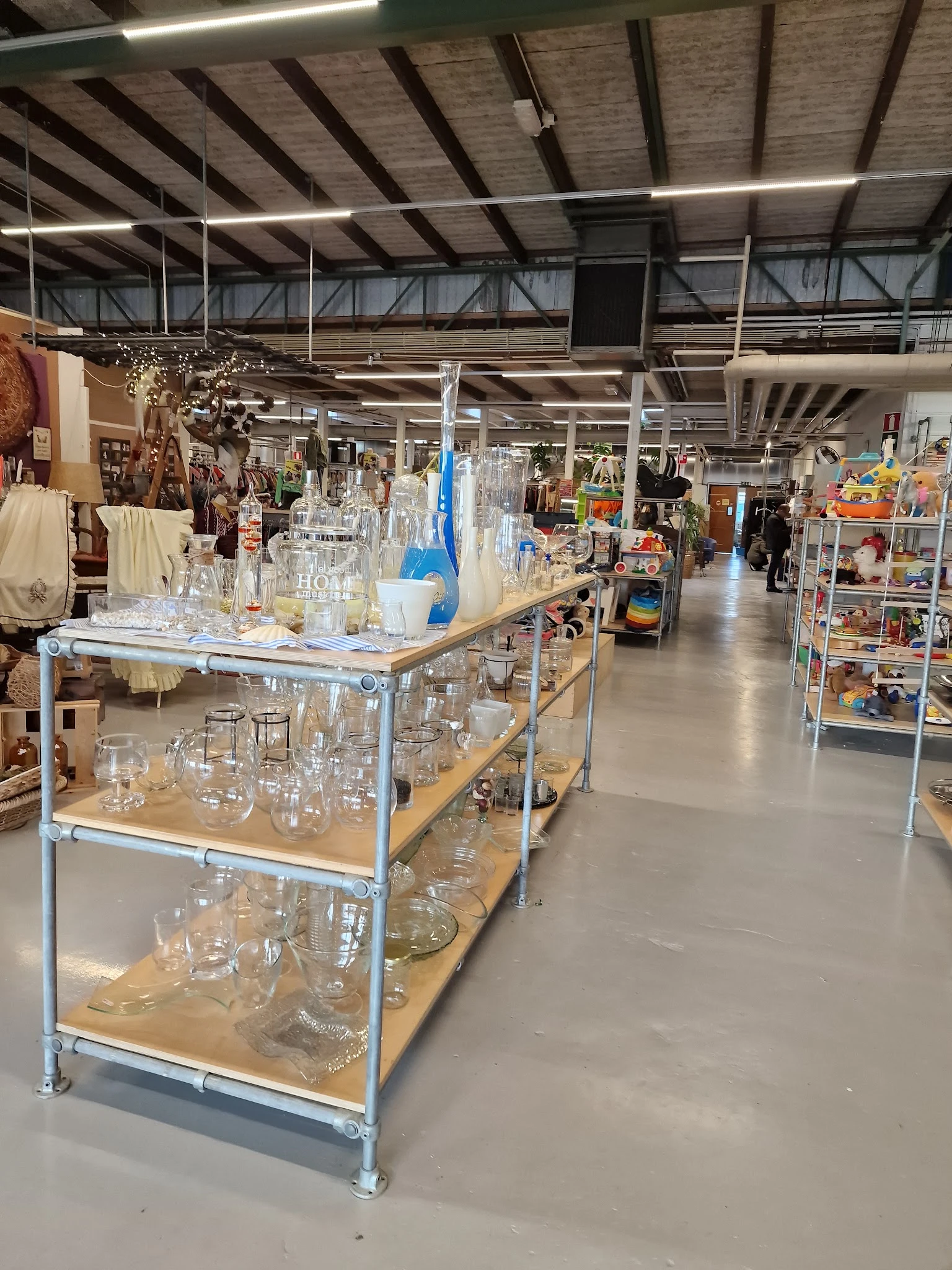 Glazen en kannen op metalen stellingen in kringloopwinkel