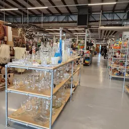 Glazen en kannen op metalen stellingen in kringloopwinkel