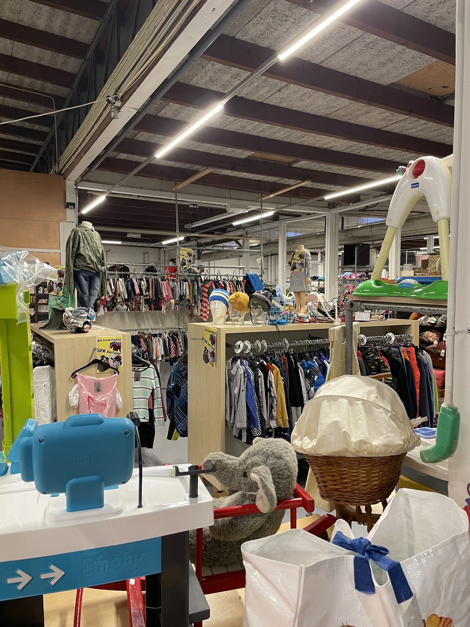 Winkelvloer met stellingen vol tweedehands kleding, speelgoed en huishoudspullen