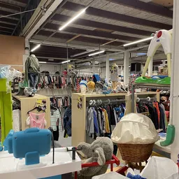 Winkelvloer met stellingen vol tweedehands kleding, speelgoed en huishoudspullen