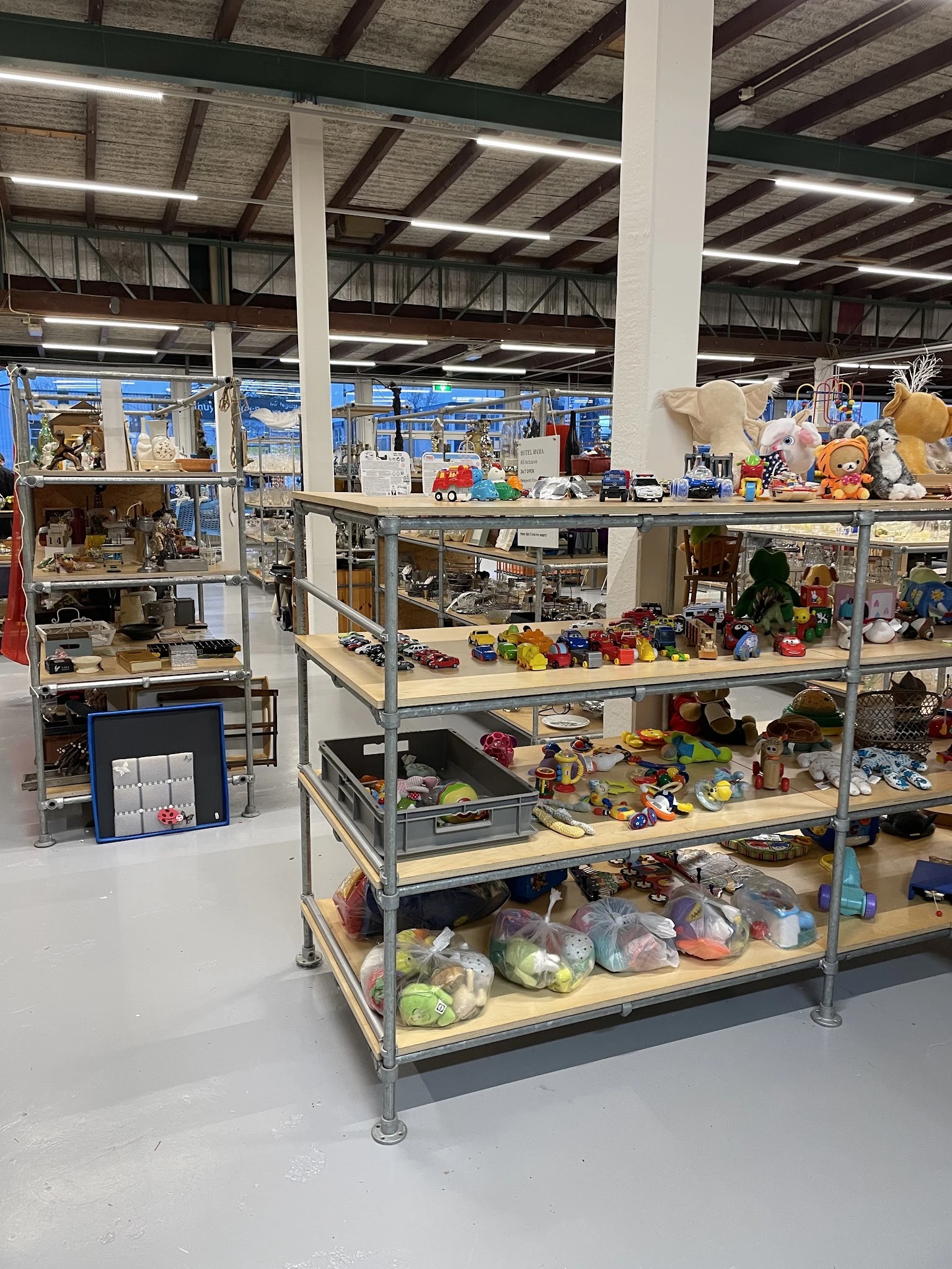 Metalen stellingkast met meerdere niveaus vol met speelgoed, knuffels, huishoudartikelen en diverse tweedehands artikelen