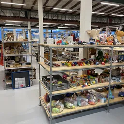 Metalen stellingkast met meerdere niveaus vol met speelgoed, knuffels, huishoudartikelen en diverse tweedehands artikelen