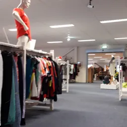 Winkelvloer met kledingrekken en mannequin in rode jurk, moderne winkelruimte met plafondverlichting