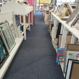 Lange gang in kringloopwinkel met stellingen en uitgestalde spullen aan beide zijden