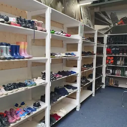 Witte stellingen met tweedehands kleding, schoenen en accessoires netjes uitgestald