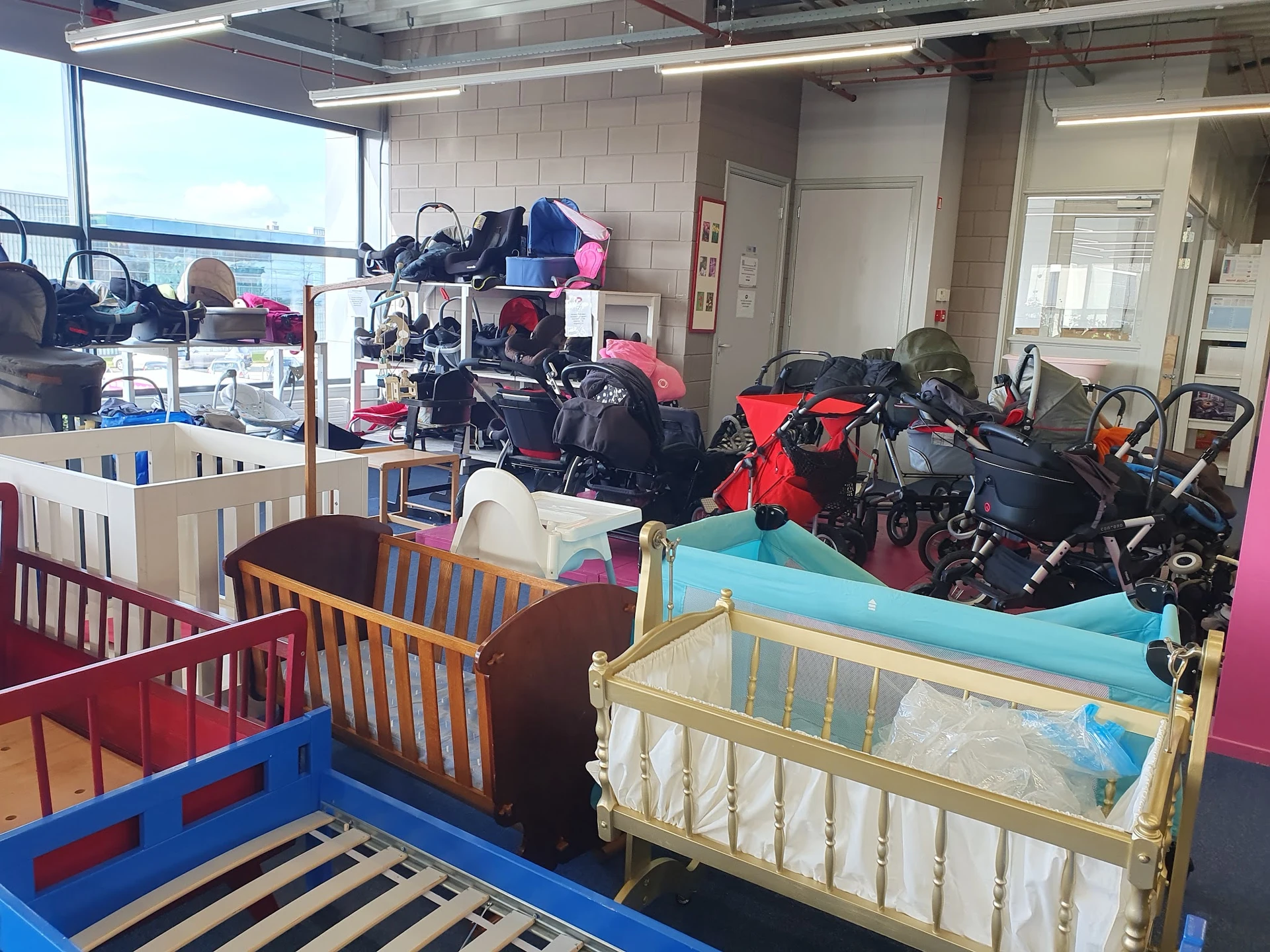Uitgestalde kinderwagens, fietsen en babymeubilair in een kringloopwinkel