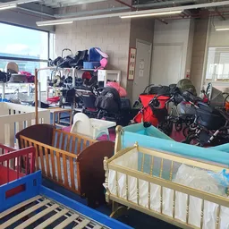 Uitgestalde kinderwagens, fietsen en babymeubilair in een kringloopwinkel