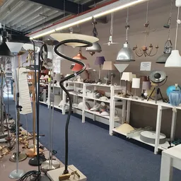 Winkelinterieur met witte stellingen vol huishoudelijke artikelen, hangende lampen en decorstukken