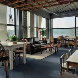 Ruime winkelruimte met zithoeken, tafels, stoelen en meubels bij grote ramen met uitzicht op water