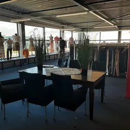 Ruime winkelruimte met kledingrekken, etalagepoppen en een tafel met stoelen in het voorplan