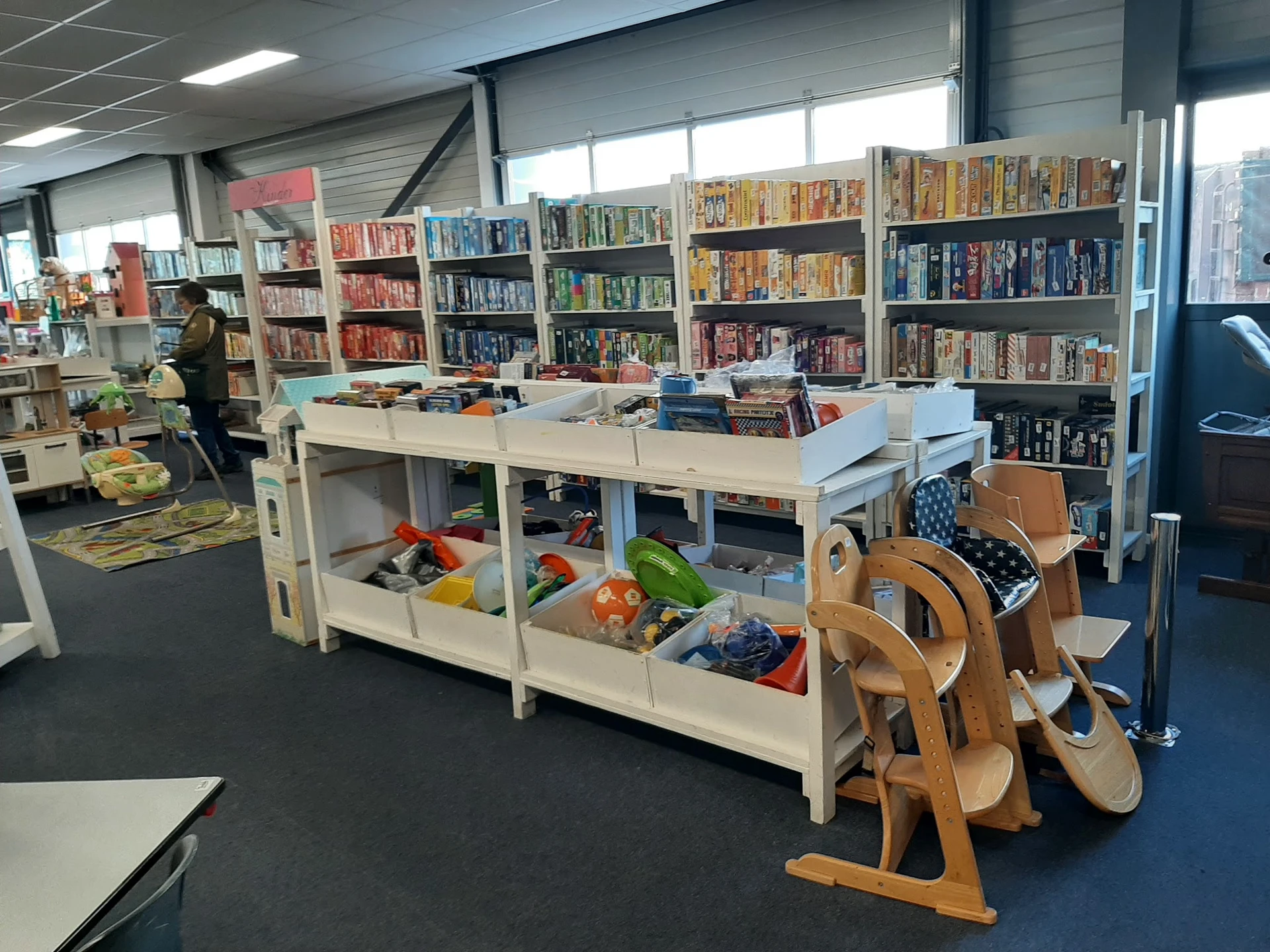 Winkelvloer met boekenrekken, speelgoed en houten instrumenten in een kringloopwinkel