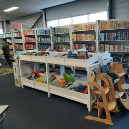 Winkelvloer met boekenrekken, speelgoed en houten instrumenten in een kringloopwinkel