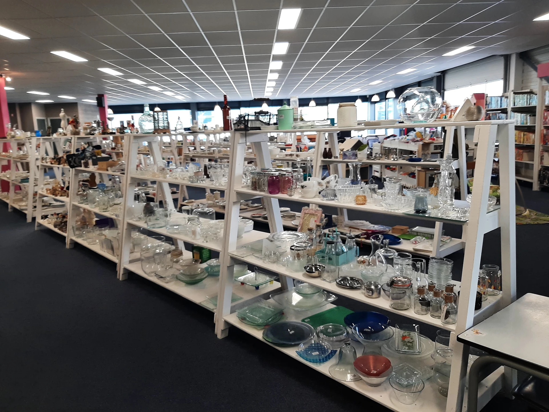 Glazen vitrinekasten met diverse decoratieve items, glazen en porselein op meerdere niveaus