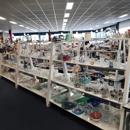 Glazen vitrinekasten met diverse decoratieve items, glazen en porselein op meerdere niveaus