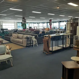 Winkelvloer met diverse meubels: banken, stoelen, tafels en kasten uitgestald in een ruime kringloopwinkel