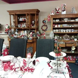 Winkelinterieur met houten meubels, tafeldecoratie en kersversiering, uitgestalde serviesgoed en decoratieve items op rekken