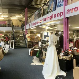 Winkelvloer met kledingrekken, etalagepoppen en diverse spullen; paarse winkelbanners zichtbaar