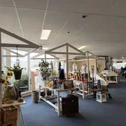 Ruim interieur van kringloopwinkel met stellingen, meubels, hangkleding en inrichtingsobjecten onder kasseinplafond met dagli