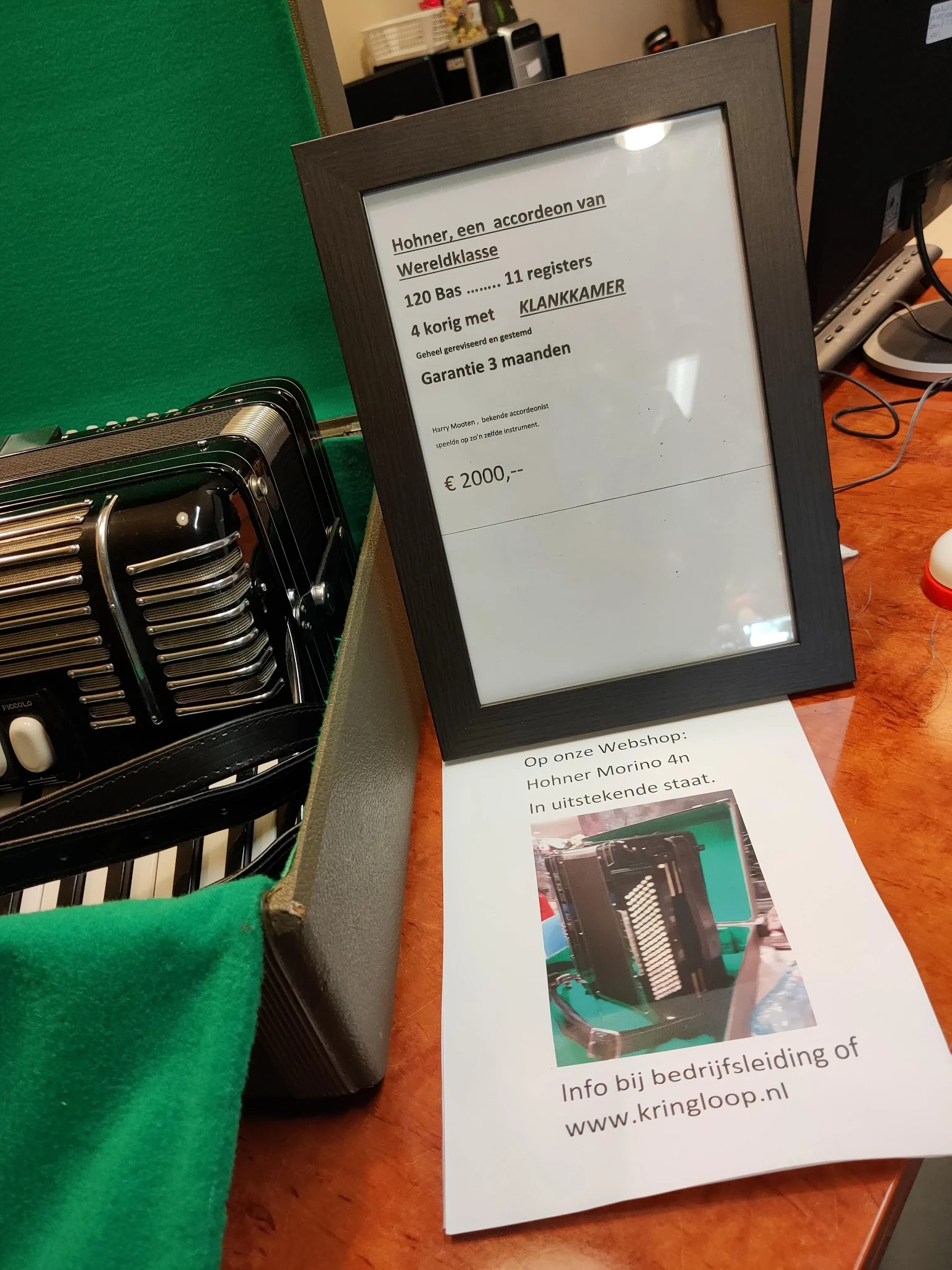 Zwarte accordeon met toetsen en bellows, naast prijskaartje met €2000,- en garantieinfo