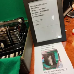Zwarte accordeon met toetsen en bellows, naast prijskaartje met €2000,- en garantieinfo
