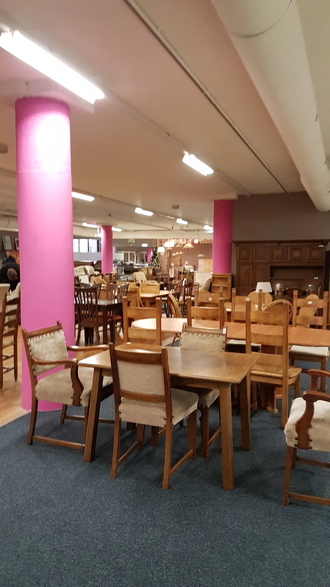 Winkelvloer met houten meubels, stoelen en tafels uitgestald tussen roze zuilen