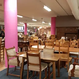 Winkelvloer met houten meubels, stoelen en tafels uitgestald tussen roze zuilen