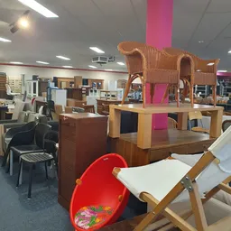 Winkelinterieur met meubels, waaronder een houten speelhuisje, houten tafel en diverse stoelen en kasten