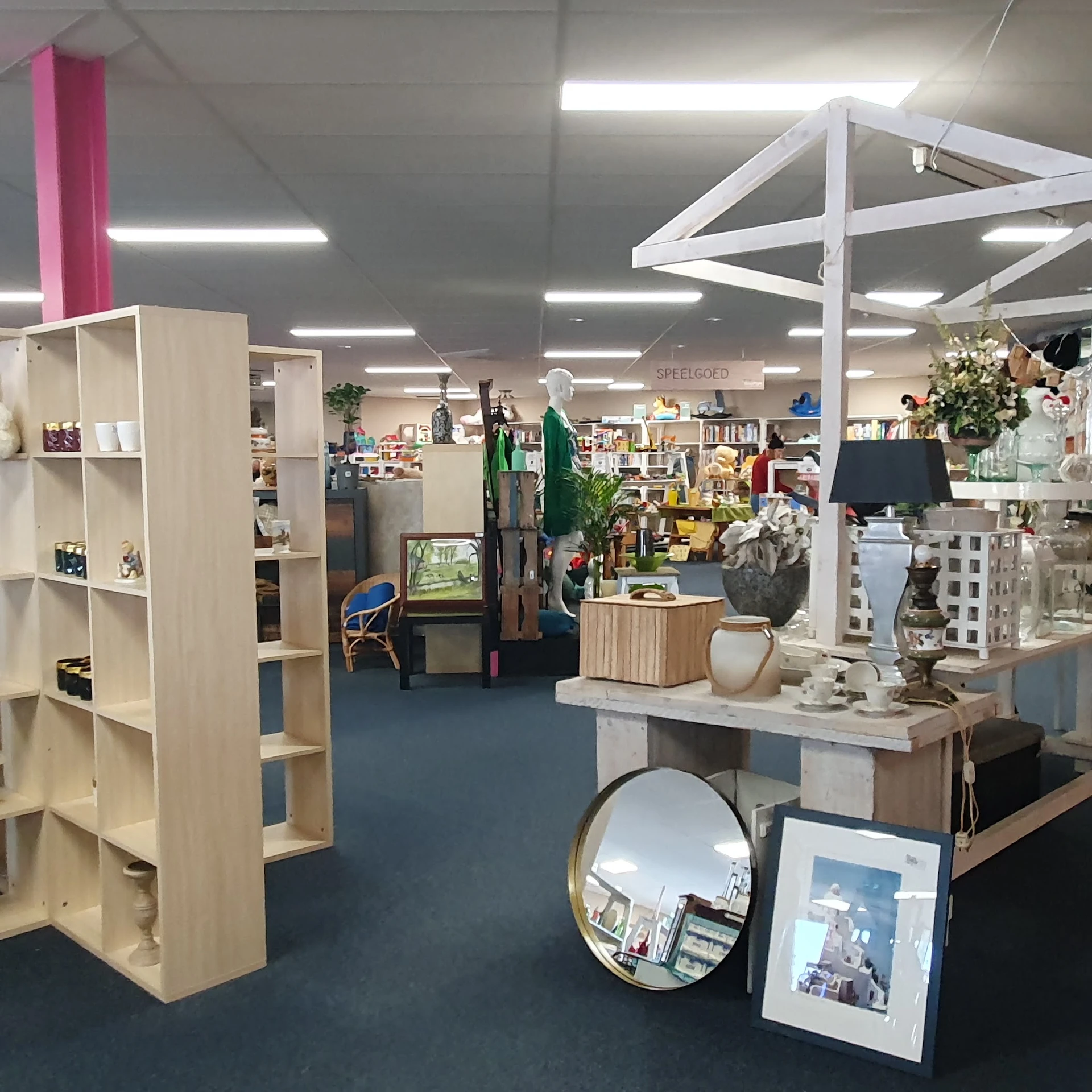 Winkelinterieur met houten stellingen, huishoudelijke artikelen, decoratie en diverse spullen