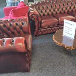 Rode Chesterfield-fauteuils en -banken in de winkelruimte met een prijskaartje