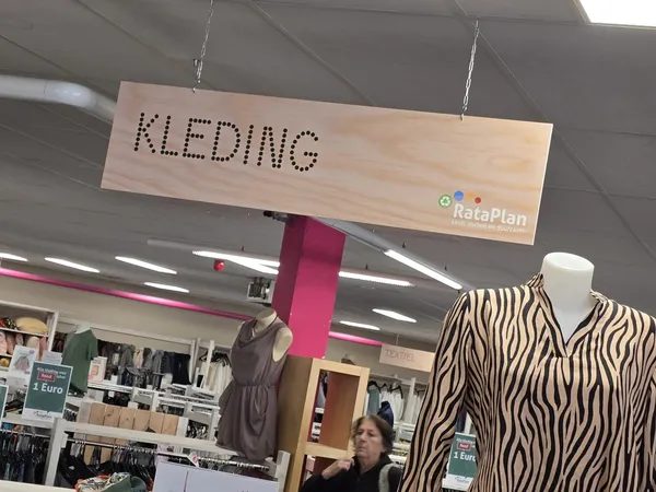 Winkelinterieur met kledingrekken, etalagepop met zebraprint blouse en houten hangbordje met 'KLEDING' opschrift