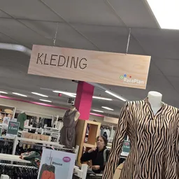 Winkelinterieur met kledingrekken, etalagepop met zebraprint blouse en houten hangbordje met 'KLEDING' opschrift