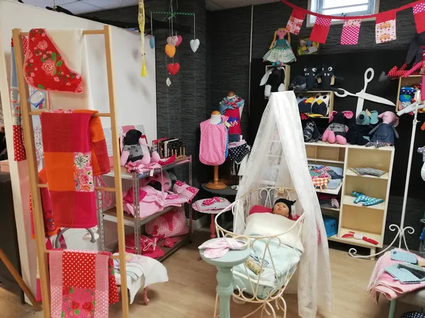 Speelgoedhoek met poppenhuis, pop en accessoires, kasten met speelgoed en kleding tegen zwarte muur met rode decoratie